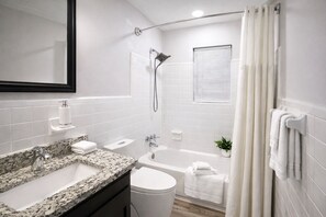 A modern bathroom with a granite countertop sink, a white toilet, a bathtub, and a shower. - Cozy 2-Bedroom Peaceful Modern Home - Monthly Discount (Riverdale)