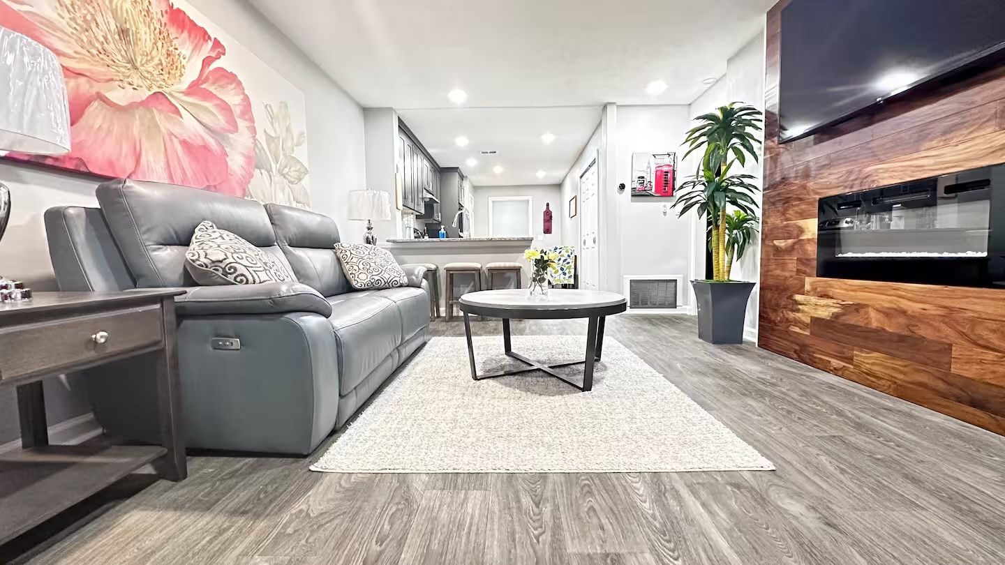 A modern living room with a grey sofa, a coffee table, and a large painting on the wall.