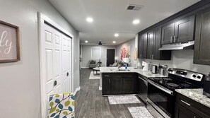 A modern kitchen with dark cabinets, a granite countertop, and stainless steel appliances. - Cozy 2-Bedroom Peaceful Modern Home - Monthly Discount (Riverdale)