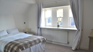 A bedroom with a bed, a window with curtains, a radiator, and a nightstand with a lamp. - The Residence, 3-bed Apt, Sleeps 6 With Parking (Lancaster)