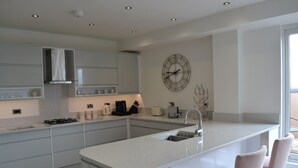 Una cocina moderna con una isla central, taburetes de bar y un reloj de pared.