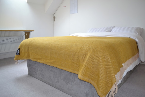 A bed with a grey headboard, a white mattress, and a mustard-colored blanket. - The Residence, 3-bed Apt, Sleeps 6 With Parking (Lancaster)