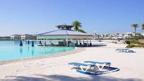 Ein Poolbereich direkt am Strand mit Liegestühlen und einem überdachten Pavillon.
