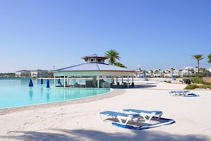 Ein Poolbereich direkt am Strand mit Liegestühlen und einem überdachten Pavillon.