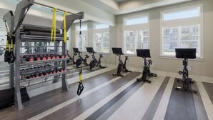 Ein Fitnessraum mit Ergometer, Gewichtelementen und einem Spiegel.
