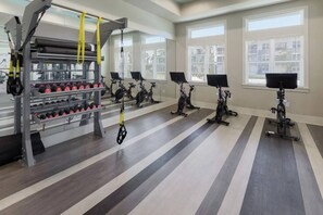 Ein Fitnessraum mit Ergometer, Gewichtelementen und einem Spiegel.