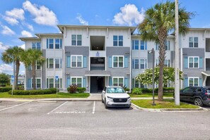 A multi-story residential building with a parking lot in front. - Plush 2BR Apt/Pool/Gym/King Bed/Beachwalk access (St. Johns County)