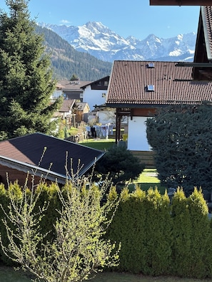 Vista de la montaña con una casa con techo de tejas y un pequeño jardín.