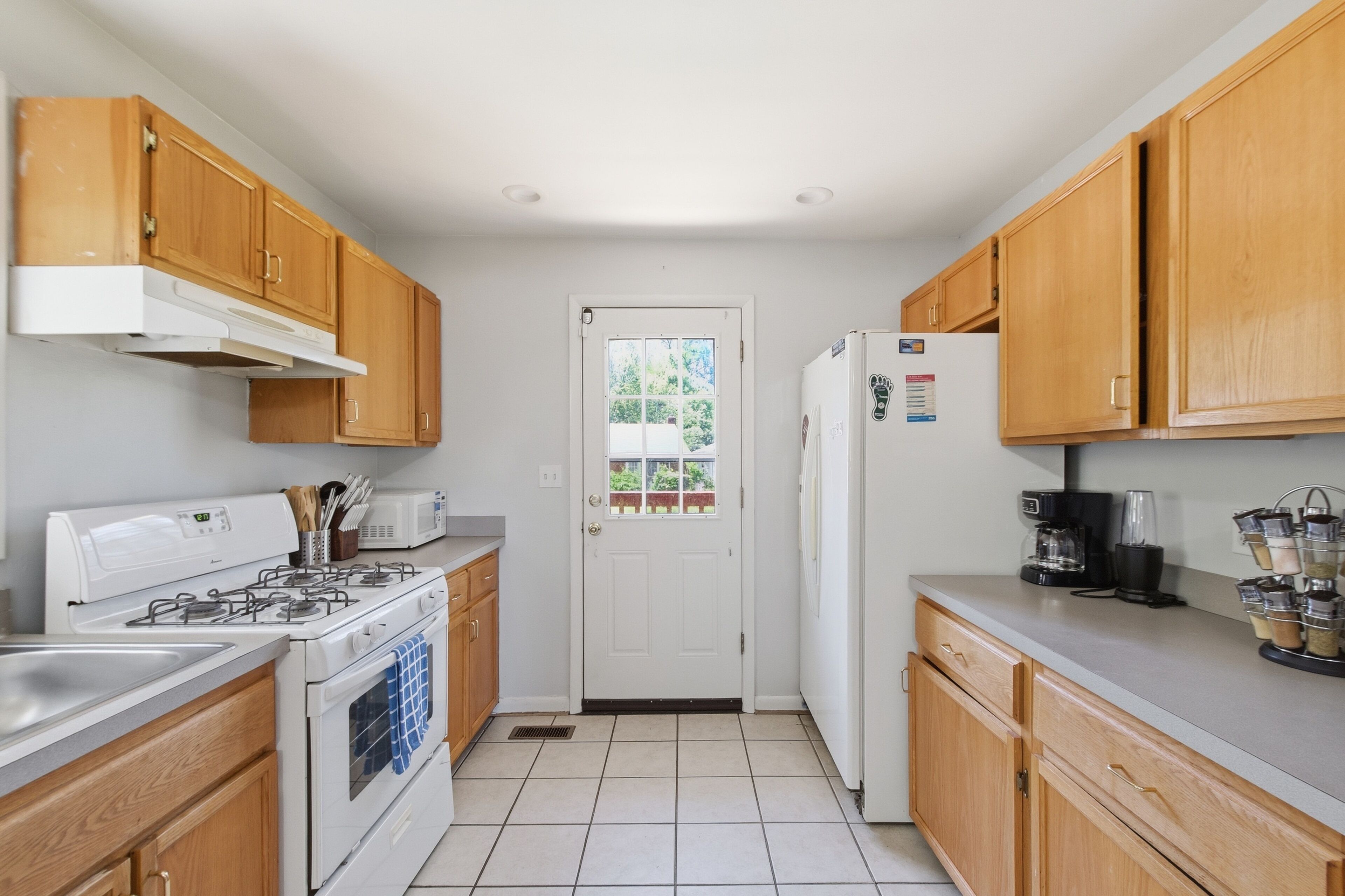 A compact kitchen with wooden cabinets, a gas stove, a microwave, and a refrigerator.