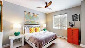 A bedroom with a bed, nightstands, a globe, a window, and a red dresser.