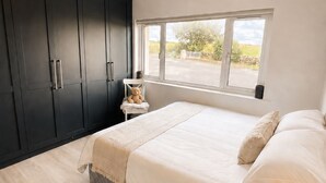 Un dormitorio con una cama grande, una mesita de noche, una ventana y armarios de madera oscura.