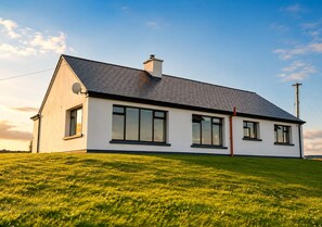 A single-story house with a sloped roof, large windows, and a chimney.