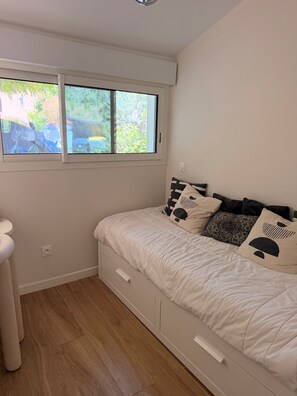 Une chambre à coucher avec un lit, une fenêtre et un mur blanc.