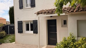 A two-story house with a gravel driveway, a front door, and a small garden area with potted plants. - Bright, air-conditioned house in Aix-en-Provence (Aix-en-Provence)