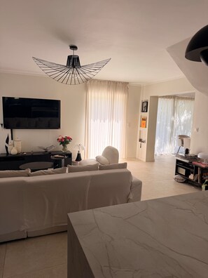 A modern living room with a flat-screen TV, a sofa, a coffee table, and a dining area with a marble table. - Bright, air-conditioned house in Aix-en-Provence (Aix-en-Provence)