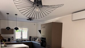 A modern kitchen with a central island, pendant lighting, and a sofa in the living area. - Bright, air-conditioned house in Aix-en-Provence (Aix-en-Provence)