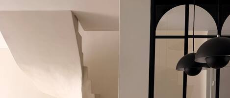 Um interior moderno com escada, janela grande e piso de mármore.