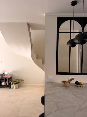 Un intérieur moderne avec un escalier, une grande fenêtre et un sol en marbre.