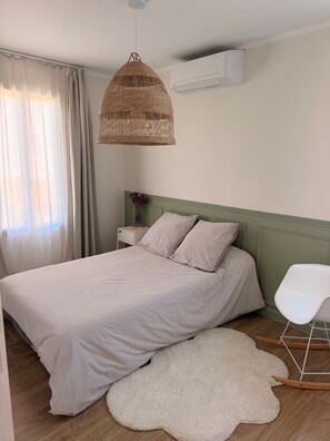 Une chambre à coucher avec un lit, un luminaire suspendu, une chaise blanche et un tapis.