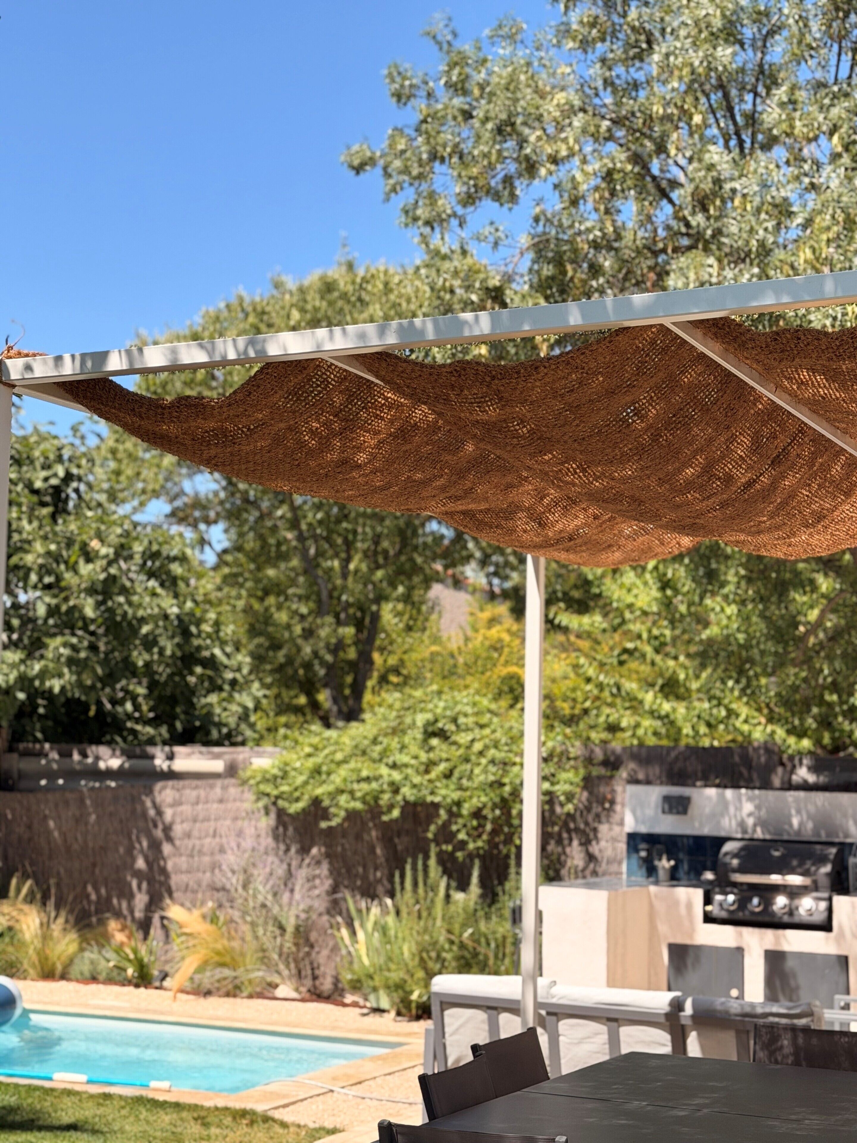 A covered outdoor area with a pool, barbecue grill, and seating.