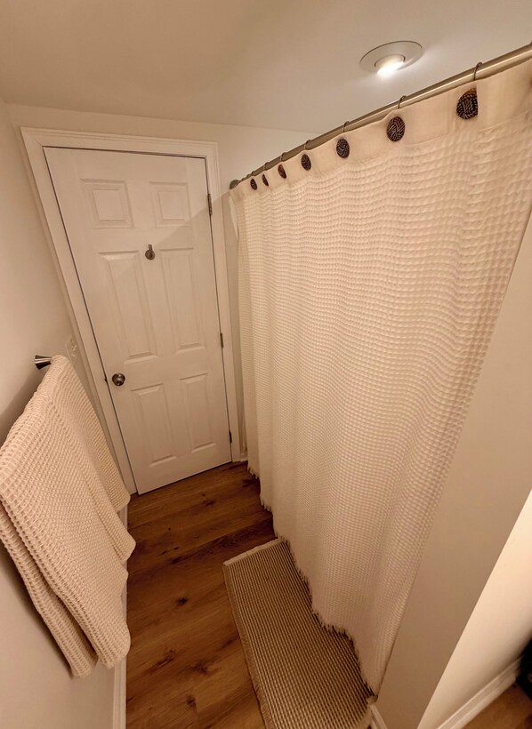 A bathroom with a white door, a shower curtain, and a towel rack.