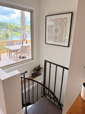 A balcony with a table and chairs, a view of a lake, and a framed artwork on the wall.