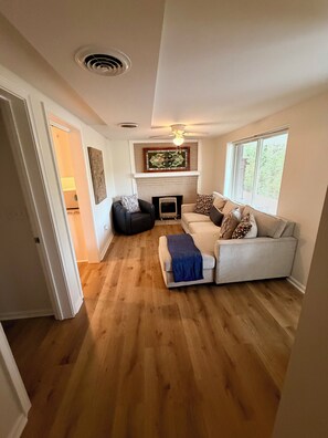 A living room with a fireplace, a sofa, a chair, and a wooden floor.