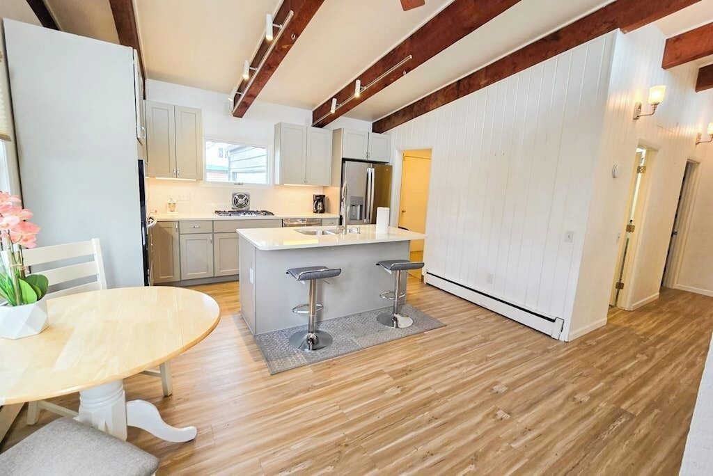 A modern kitchen with a central island, bar stools, and wooden flooring.