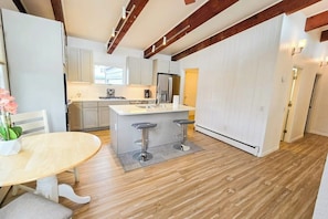 A modern kitchen with a central island, bar stools, and wooden flooring. - Easy Single-level Anchorage Home Near Parks and Trails (Anchorage)