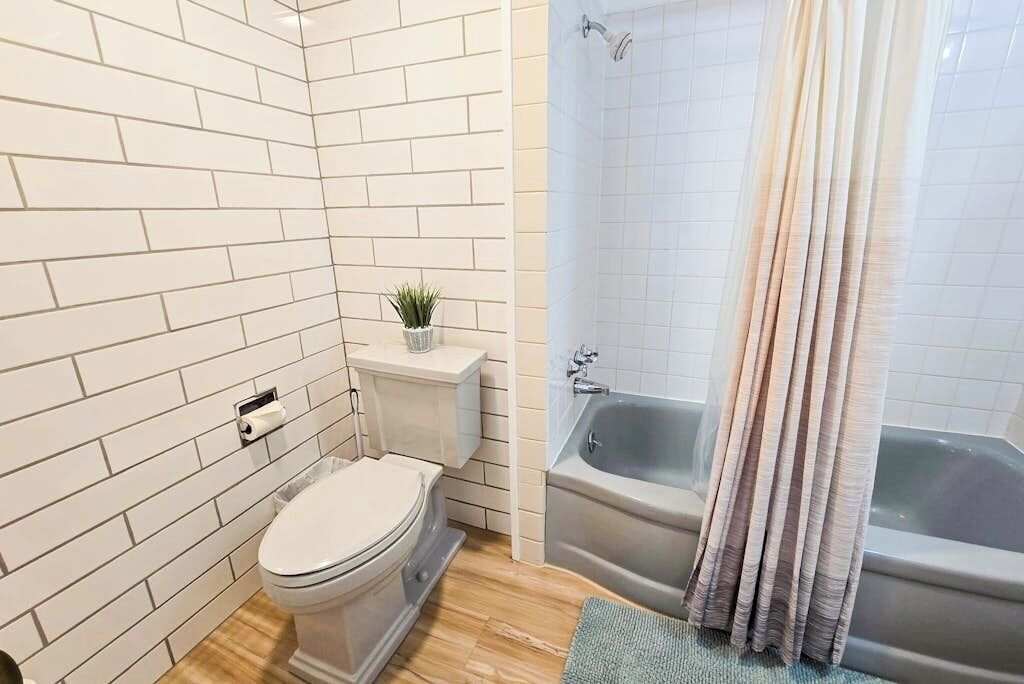 A bathroom with white tiled walls, a toilet, a sink, and a bathtub.