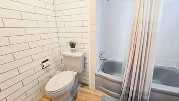 A bathroom with white tiled walls, a toilet, a sink, and a bathtub.