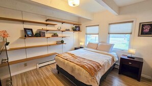 Ein Schlafzimmer mit Bett, Nachttischen, integrierten Regalen und einem Fenster.