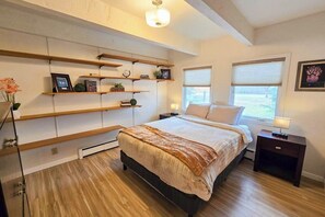 Ein Schlafzimmer mit Bett, Nachttischen, integrierten Regalen und einem Fenster.