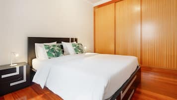 A neatly made bed with white bedding, a bedside lamp, and a nightstand with a modern design.