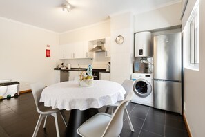 Une cuisine de taille réduite avec une table ronde, des chaises, un lave-linge et un réfrigérateur.