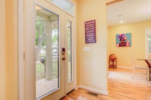 A hallway with a glass door leading to a backyard, a motivational quote on the wall, and a dining area with a table and chairs. - Spacious Home, Dual King Suites, Central Manhattan (Manhattan)
