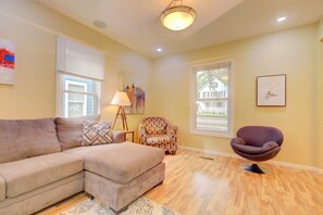 A living room with a sectional sofa, a patterned armchair, a purple chair, a floor lamp, and artwork on the walls. - Spacious Home, Dual King Suites, Central Manhattan (Manhattan)