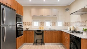 A modern kitchen with stainless steel appliances, wooden cabinets, and a tiled backsplash.