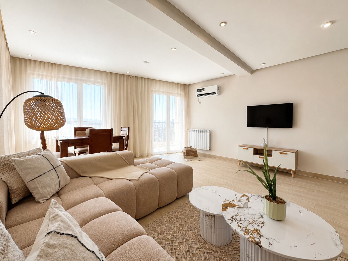 Una sala moderna con un sofá seccional, una mesa de centro, un televisor y un comedor.