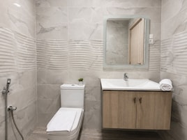 Un baño con ducha, inodoro, lavamanos y armario.