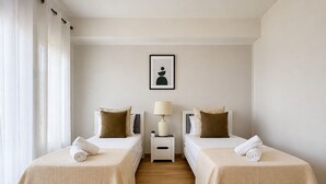 A hotel room with two beds, a nightstand with a lamp, and a framed picture on the wall.