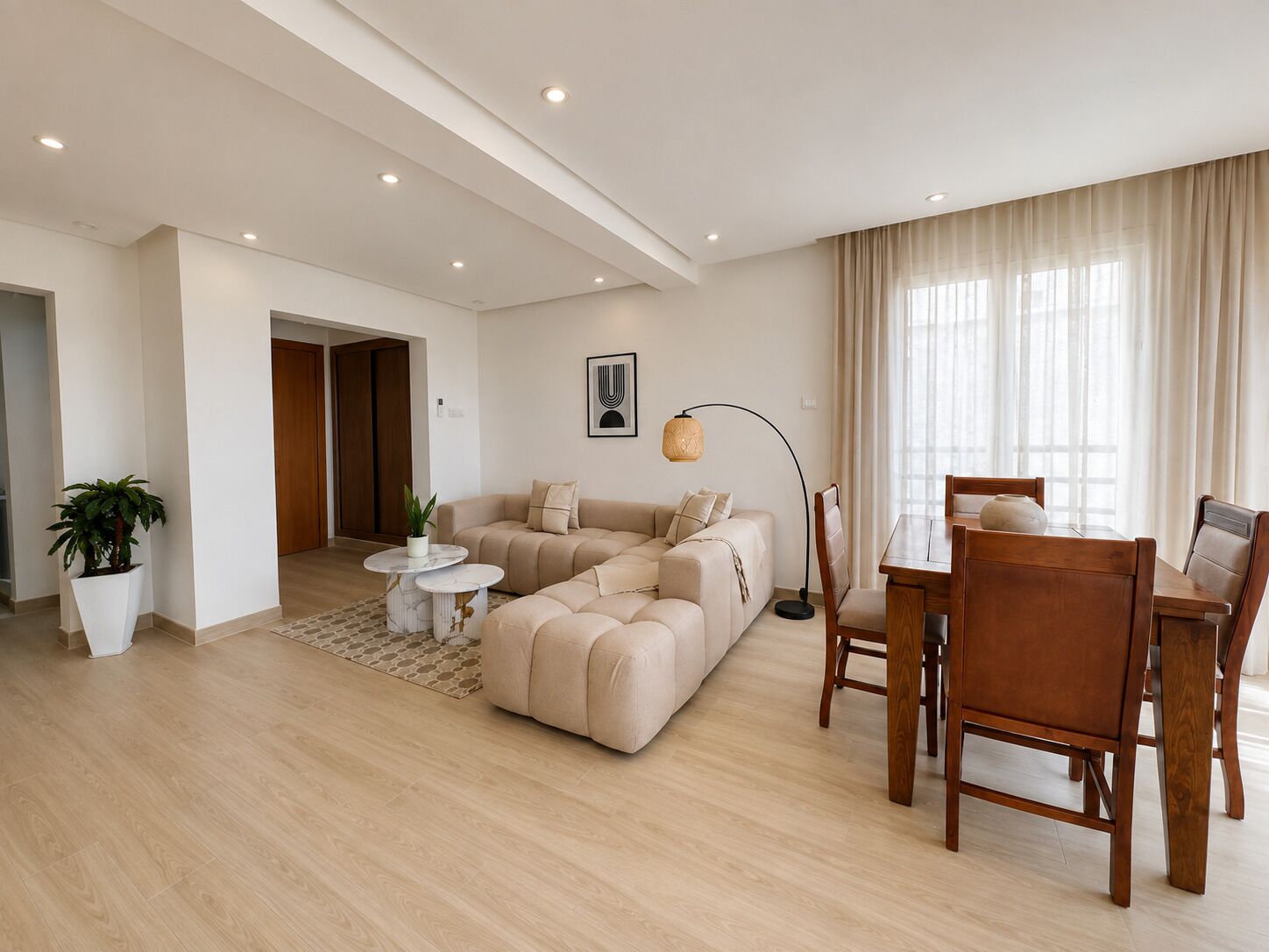 Un salon moderne avec un canapé d’angle, une table à manger avec des chaises, une lampe sur pied et une plante en pot.
