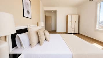 Een slaapkamer met een bed, nachtlampen, een kledingkast en een deur naar een andere kamer.