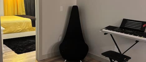 Une pièce avec un lit, un support pour guitare noir et un clavier.