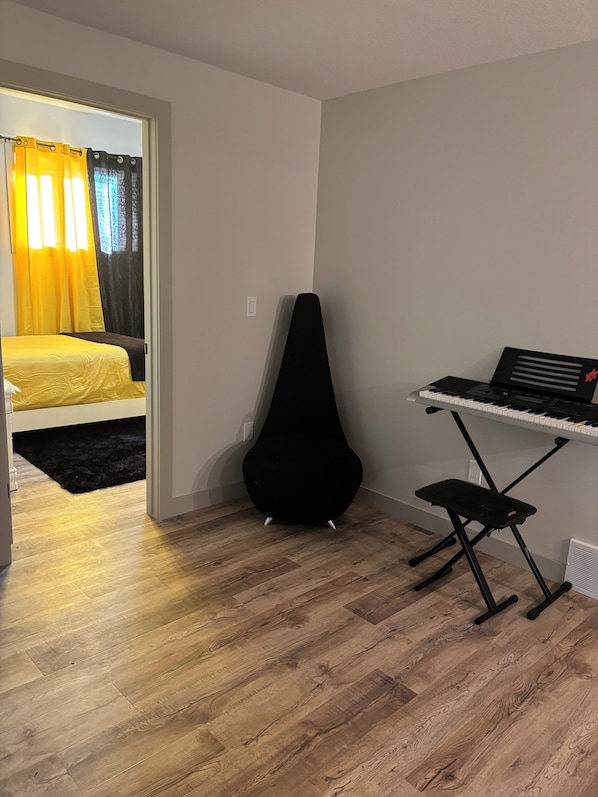 A room with a bed, a black guitar stand, and a keyboard.