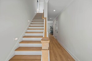A staircase with wooden steps and a white handrail leading to a landing. - Rooftop Retreat: Steps to Downtown Square (Murfreesboro)