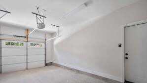 Een garage met een witte deur, een raam en een betonnen vloer.