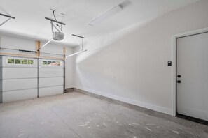 A garage with a white door, a window, and a concrete floor. - Rooftop Retreat: Steps to Downtown Square (Murfreesboro)