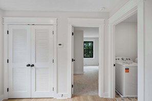 A room with a white door, a window with a view of trees, and a washing machine. - Rooftop Retreat: Steps to Downtown Square (Murfreesboro)