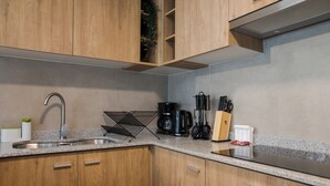 Moderni keittiö, jossa on puiset kaapit, ruostumattomasta teräksestä valmistettu pesuallas ja kahvinkeitin.